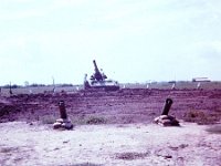 The powder canisters sticking out of the ground in a circle around the gun were reference aiming points that were used to help relay the gun when it had to “swing trails” to another azimuth of fire.